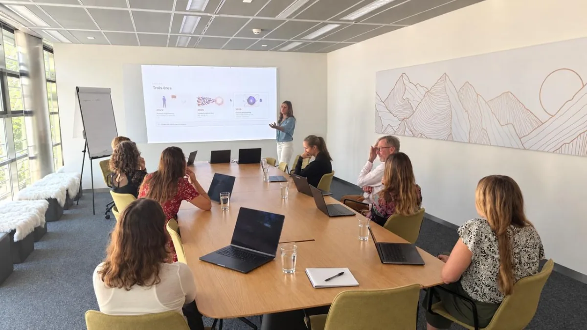 Formation en petit groupe à Genève : huit personnes autour d'une table, chacune sur son ordinateur portable, face à la formatrice